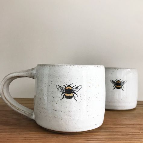 Bumble Bee mug by Heather Mathieson This gorgeous rustic ceramic bee mug has been wheel-thrown using a brown, stoneware clay - glazed with a food safe, glossy white glazeIt features a decal of one of Heather's bumble bee linocut images, which is an original designThe base is unglazed giving a lovely, rich contrast of textures and colours between the glaze and the raw clay bodyEach bee mug is handmade so please expect each one to be different in texture / detail +... Diy Keramik, Mug Diy, Bee Mug, Cerámica Ideas, White Mugs, Pottery Painting Designs, Rustic Ceramics, Keramik Design, Painted Mugs