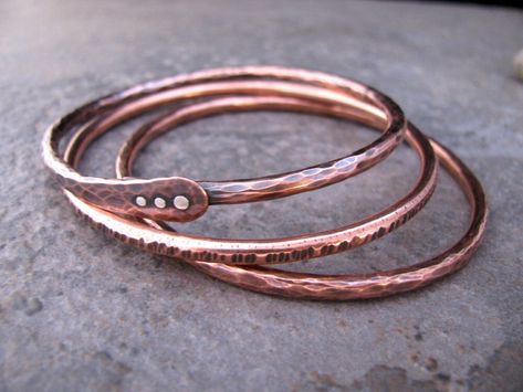 I made these copper bangles from thick 8 gauge wire.  There are 3 to a set. One is hammered all over, one is textured with hammered lines and the last one is a smaller version of my riveted bangle. It is hammered and features 3 sterling silver rivets. They are all oxidized and polished to show off the textures. To measure your bangle size put your hand in the same position as when you slip the bangle on, then measure the widest part around your hand. This can be done with a cloth type measuring Copper Jewelry Diy, Rivet Jewelry, Copper Bangles, Copper Bracelets, Copper Jewellery, Metalsmithing Jewelry, The Bangles, Bangle Bracelet Set, Wire Wrapped Bracelet