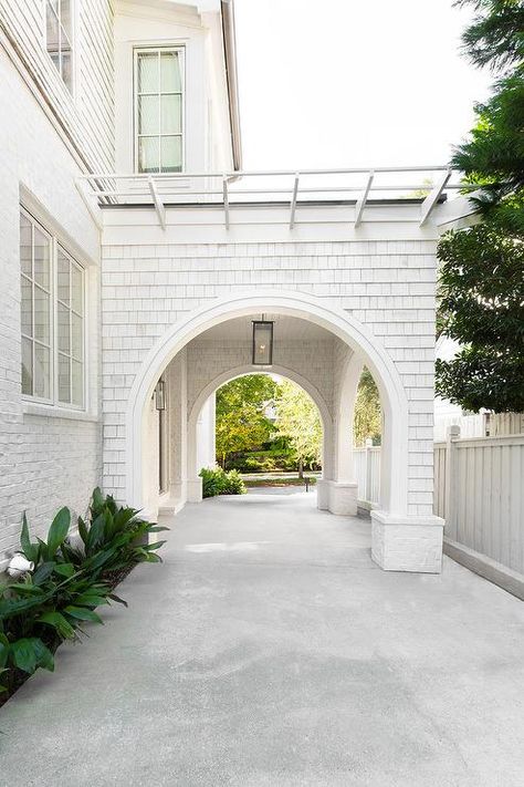 A white shingled home boasts a concrete driveway that leads to a white port cochere lit by a glass and bronze lantern. Porte Cochere, Carport Designs, Shingle Siding, Concrete Driveways, Casa Exterior, Transitional House, White Brick, Dream House Exterior, Driveway