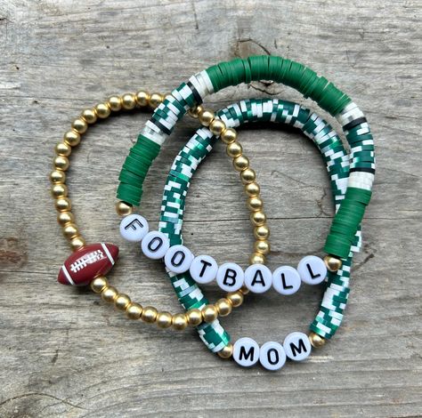 These are fun bracelets that are personalized perfectly for you! This stack is a set of {3} bracelets. The set includes two Heishi disc bracelets (the words can be changed) & a gold bracelet with a ball bead on it.  I change the bead color to match your school/team colors. I will also change the 'football' bead to whichever sport you choose. These stacks can be personalized, and bracelets added. You can reach out to me with any questions or personalization ideas! If you want bracelets added, rea Diy Team Bracelets, Sports Teams Clay Bead Bracelets, School Color Clay Bracelets, Football Bracelet Diy, Football Mom Bracelet, School Spirit Beaded Bracelets, Clay Bead Bracelet Ideas Football, Team Beaded Bracelets, Volleyball Clay Bead Bracelets