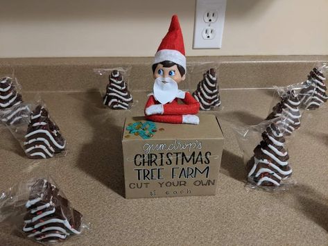 Chocolate tree cakes surrounding the elf on the shelf at a hand made Christmas tree farm stand Elf Christmas Tree Farm, Elf On The Shelf Tree Farm, Elf Ideas For Toddlers, Shelf Christmas Tree, Hermey The Elf, Christmas Monkey, Elf Games, Elf Ideas Easy, Elf Crafts