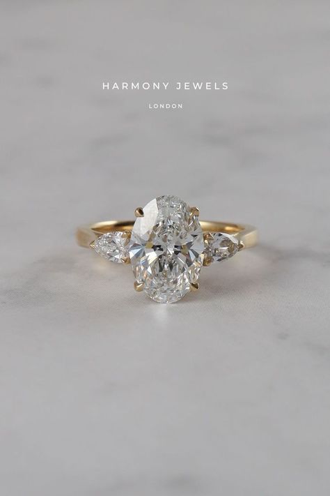 Side Stone Wedding Rings, Harmony Jewels London, 3 Stone Oval Engagement Ring Yellow Gold, Gold Oval Engagement Ring Side Stones, Oval Ring With Accent Stones, Oval With Trillion Side Stones, Oval Diamond Side Stones, Soft Gold Engagement Ring, 3 Stone Setting Engagement Ring