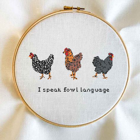 This image is a cross stitch pattern featuring three chickens in a pixelated design as befits a cross stitch pattern template. The three chickens featured are black and white on the left, brown and orange in the center, and grey and black on the right. There is text below the chickens stating "I speak fowl language". The cross stitch ring is a light wooden ring with a brass metal fixture on top keeping tension on the right to hold the fabric in place. Best Friend Cross Stitch, Chicken Embroidery Patterns, Farm Cross Stitch, Stitch Template, Rooster Cross Stitch, Chicken Embroidery, Chicken Cross Stitch, Whimsical Diy, Fowl Language