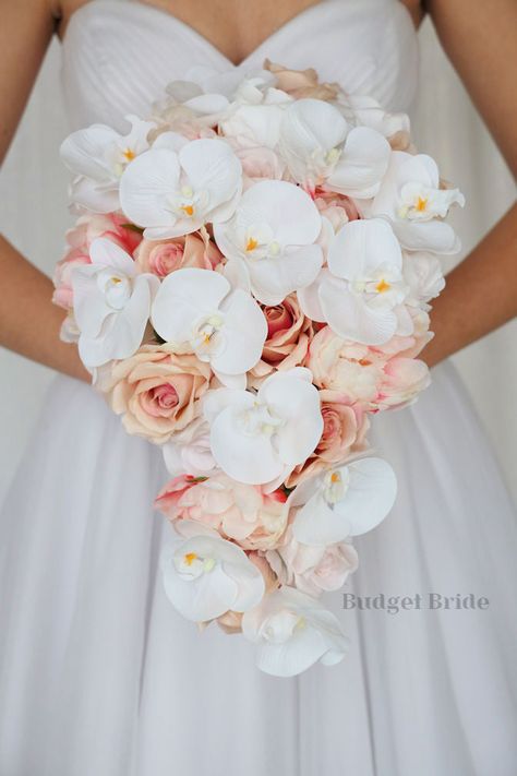 This lovely assortment of roses in a pink champagne color, with pink peonies and white orchids is bound to turn heads on your wedding day. This lovely cascading brides’ bouquet from the Sophie collection is an absolutely breathtaking arrangement for any bride to be, in any season. The stunning white orchids complete the look and add a delicate realism to this beautiful bouquet. This bouquet is 10” wide, 18” long, and is crafted by our in-house florists without using a foam base to anchor the flo Peony Rose Orchid Bouquet, Pink Cascade Bouquet, Wedding Bouquets Without Roses, Wedding Bouquets Orchids And Roses, Beach Pink Wedding, Champagne And Pink Wedding, Elegant Theme Wedding, Roses And Peonies Bouquet, Rose And Orchid Bouquet