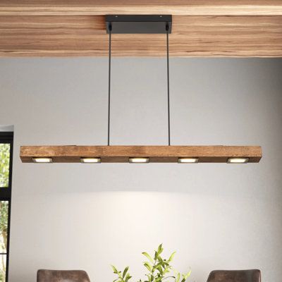 This 6-light linear pendant combines modern and rustic elements to create a striking focal point anywhere in your home. A large rectangular solid wood block hovers over your kitchen island or dining table, with LED bulbs integrated into it - four panels underneath and two above. It hangs with the help of two height-adjustable wires, and the black-finished iron canopy is compatible with sloped ceilings for your convenience. This luminary also works with dimmer switches, so you can easily control Pendant Lighting Over Dining Table, Over Island Lighting, Linear Lighting Design, Lights Over Dining Table, Track Lighting Kitchen, Kitchen Island Lighting Modern, Lights Over Kitchen Island, Lamps For Kitchen, Dining Room Light Fixture