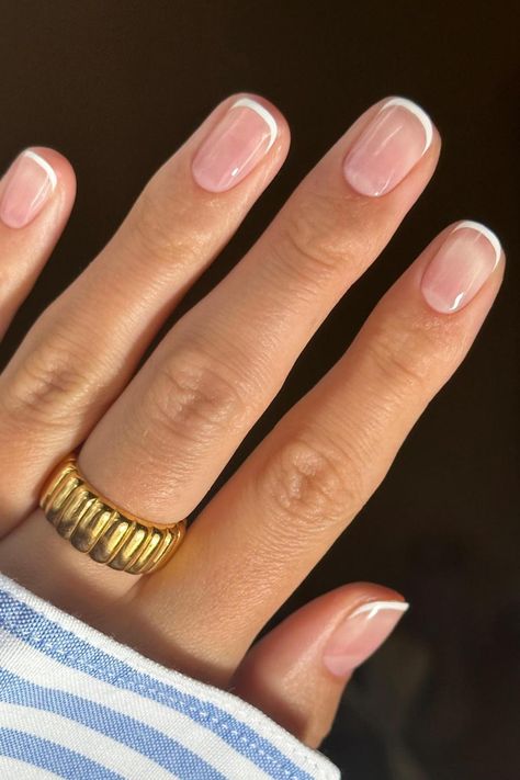 Timeless elegance shines through on these squoval-shaped nails, adorned with a classic French tip. The combination of a natural pink base and perfectly rounded, crisp white tips exudes sophistication and cleanliness, making it a versatile choice for any event. Embrace understated chic with this classic French manicure. // Photo Credit: Instagram @saskiafenwick Small Tip French Manicure, French Tip Gel Manicure Short, French Nail Short Nails, Colored Tip French Nails, Short Elegant Gel Nails, Short Modern French Nails, Pale French Nails, Natural Color French Tip, Round Short French Tip Nails