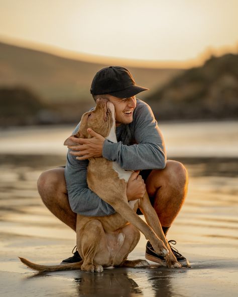 Man cuddles dog on the beach during sunset. Dog licks his face. Man Dog Photography, Cool Dog Photography, Man And His Dog Photography, Dog And Man Photography, Men With Dog Photoshoot, Men And Dogs Photography, Pet Beach Photography, Dog On Beach Photography, Backyard Lifestyle Photography