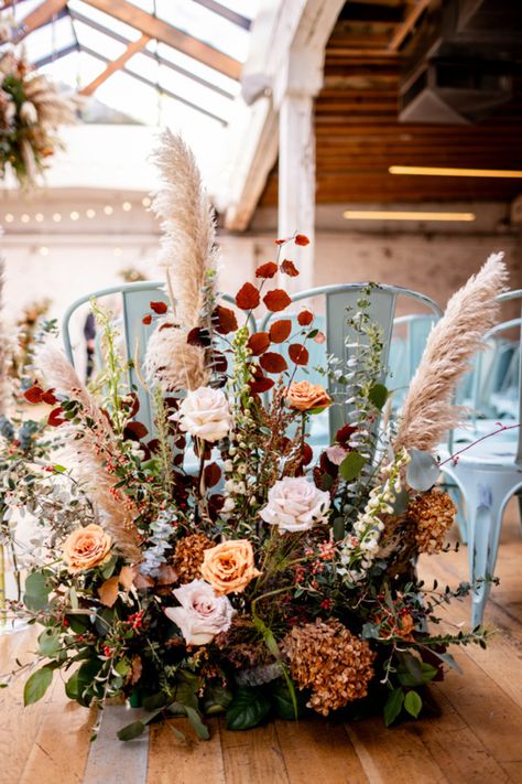 Chicago florist, Romee Willow Florals, created these floral hedges for a fall wedding ceremony at The Joinery. Elements include toffee roses, pampas grass, white dahlias, eucalyptus, and other dried elements in these artistic floral arrangements. We repurposed these floral hedges and placed them in front of the sweetheart table during the reception. To see more photos of their textured, autumnal floral decor by Allison Williams Photography, visit our blog through the link. Pampas Grass And White Rose Bouquet, Dried Floral Arch Wedding, Fall Wedding Aisle Flowers, Eucalyptus Fall Wedding, Dried Flower Table Arrangements, Fall Floral Arrangements Wedding, Fall Wedding Ceremony Flowers, Autumn Flowers Wedding, Floral Hedge