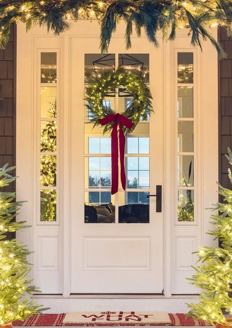 white front door with wreath with twinkle lights and red bow Light Up Christmas Wreaths, Front Door With Wreath, Exterior Christmas Decor, Front Porch Christmas Decorations, Porch Christmas Decorations, Exterior Christmas Decorations, Porch Garland, White Front Door, White Christmas Lights