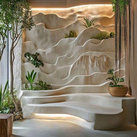 Transform interiors with sculptural plaster walls inspired by nature. This wave-like plaster design, enhanced with built-in planters and soft lighting, creates a serene and organic aesthetic, perfect for modern spaces. Ideal for biophilic design lovers, plaster’s versatility as a building material allows for creating immersive and calming environments that connect with nature. Nature Inspired Office Design, Biophilic Artwork, Rockwall Design, Spa Wall Design, Plastering Walls Ideas, Luxury Wall Design, Biophilic Design Interiors, Building Sculpture, Building Materials Architecture