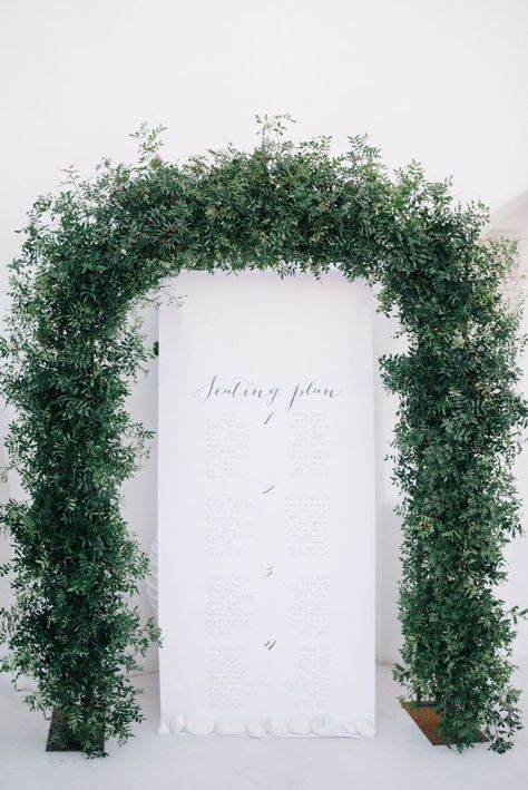 Rustic greenery arch wedding escort seating char Greenery Arch, Arch Wedding, Modern Minimalist Wedding, Santorini Wedding, Event Signage, Wedding Ceremony Flowers, Greenery Garland, Greece Wedding, Ceremony Flowers