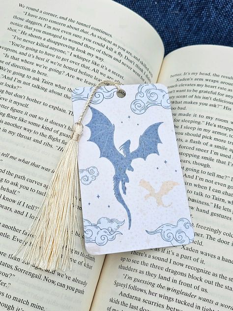 Holographic Dragon bookmark, the perfect accessory for all book lovers and book nerds alike! Each bookmark is designed and created with care and love! This Dragon bookmark is a double sided bookmark that is versatile and charming, making it the ideal reading accessory for any books. The glossy holographic finish adds a touch of vibrancy, making the design stand out. The tassel makes it super easy to find your page and continue reading! Listing Includes: - One (1) Double sided Holographic Fantasy Dragon bookmark with tassel. - Choose from 7 different color tassels.  - Bookmark size is 2.5 in x 4.17 in. - The bookmark is printed on premium cardstock paper and it is laminated with holographic laminate. - Dragon Bookmark, Holographic Bookmark with Tassel, Page Marker, Double Sided Bookmark, Fa Page Marker Ideas, Fantasy Bookmark Ideas, Dnd Bookmark, Fancy Bookmarks, Bookmarks Aesthetic, Fantasy Bookmarks, Dragon Bookmark, Best Bookmarks, Bookmark Size