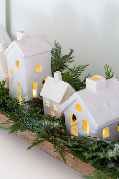 Christmas tabletop display using white ceramic houses lined up in a dough bowl with greenery around them. Ceramic Houses Christmas Decor, White Ceramic Christmas Village, White Village Christmas Houses, White Ceramic Houses Christmas, White Christmas Village Display, Ceramic Houses Christmas, White Ceramic Houses, White Christmas Village, Diy Chalk Paint Recipe