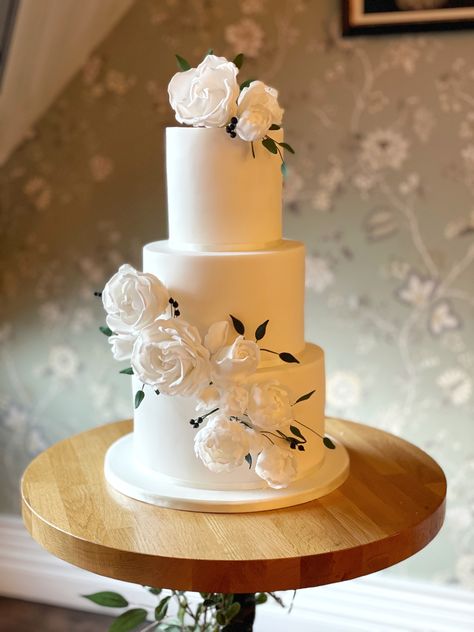 3 tier wedding cake covered with fondant, finished with handmade white sugar iced roses, leave and berries 3 Tier Wedding Cake Fondant, Simple White 3 Tier Wedding Cake, Simple Wedding Cake 3 Tier, Simple 3 Tier Wedding Cake, 3 Teir Wedding Cake, Simple White Wedding Cake, Simple White Wedding, Reception Entertainment, Roses With Leaves