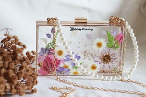 New drops: Beautiful floral resin clutch 👜 Elevate your style quotient in a blink with these exquisite floral resin clutches. Available in all these designs, check them out now! DM to order or enquire for prices! 💌 #resinclutch #resinclutches #resinclutchbag #resinpurse #resinbag Resin Art Purses, Resin Clutch Diy, Floral Clutch Bag, Resin Clutch Bag, Resin Clutch, Resin Bag, Floral Resin, Acrylic Clutch, Elevate Your Style