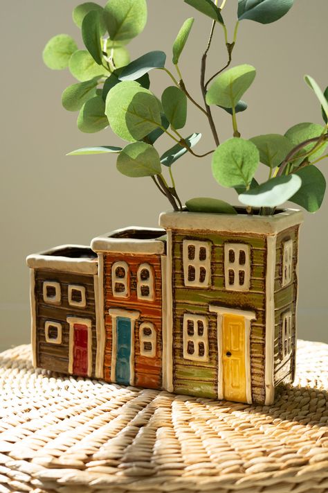 This ceramic village planter features three tiered houses in a row with room for blooms, pencils, or other essentials. This colorful trio is a great addition to your desk or mantle, or anywhere you need a sprig of something new. Grab a set to use as bookends or a gift to the realtor in your life. Ceramic Imported Brand: Kalalou Ceramic Vase Display, High School Clay Projects Ceramic Art, Handmade Pottery Vases Clay, House Decor Gifts, Ceramic Mail Holder, Ceramic Bookends Ideas, Slab Ceramics Projects, Cute Ceramic Projects, Ceramic Houses Ideas