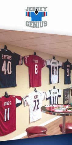 The patented Jersey Genius display is the best way to display a sports jersey, t-shirt and more! Easily adjusts to professionally showcase your jerseys. Turn any wall into a beautiful display of your favorite teams and players. The best part is you can easily take them down and put them back up anytime! Only from Jersey Genius Football Jersey Display Ideas, Garage Games, Sports Jersey Display, Hockey Jersey Display, Framing Pictures, Basement Shop, Jersey Hanger, Bike Workshop, Display Hangers