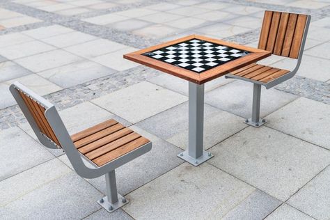 Model is a chess set consisting of a table with a chess board and two chairs with a backrest and one leg. The table and armchairs are made of wood on a steel structure. | Modern street furniture for public spaces | City Market, Poland Outdoor Chess Table, Outdoor Chess, Chess Table, Furniture Manufacturing, Urban Furniture, City Market, Urban Architecture, Street Furniture, Smart City