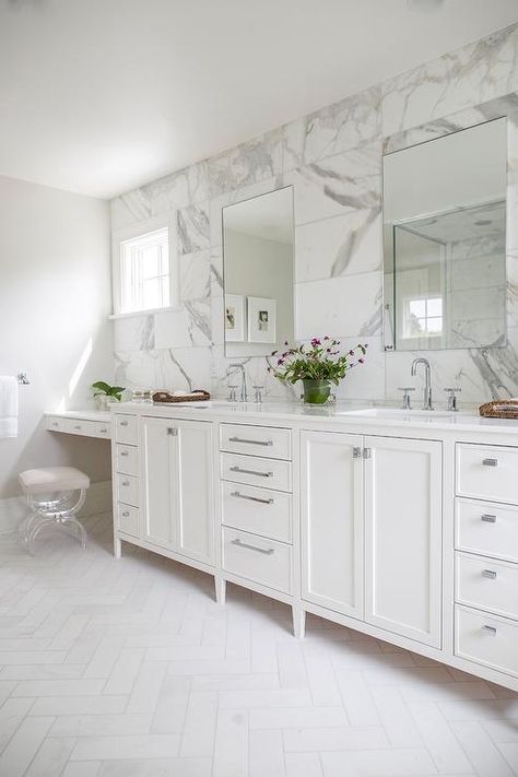 Honed white marble herringbone floor tiles lead to a white dual bath vanity adorned with polished nickel hardware and a white quartz countertop finished with rectangular sinks and polished nickel faucets fixed beneath frameless mirrors mounted to a large gray and white marble subway wall tiles. Marble Herringbone Floor, Bathroom Vanity Stool, Marble Herringbone, Double Sinks, White Bathroom Tiles, Transitional Bathroom, Paint Colors Benjamin Moore, Herringbone Floor, Benjamin Moore Paint