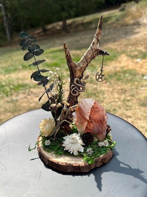 This beauty is mounted in a 5.5" wood slice. It contains a unique Roe Deer antler shed wrapped with a bronze colored craft wire and adorned with a pendant. The piece features a gorgeous fire quartz Freeform crystal, a brass praying mantis and snake, as well as dried flowers.  The praying mantis is often associated with good fortune and luck. In some cultures, the mantis is viewed as symbol of someone who has clairvoyant abilities and is a master of the art of meditation. Fire quartz enhances the ability to find balance, focus, and calm making this duo a perfect pair.  Due to the nature of the crystal and antler used, this piece is truly one-of-a-kind and cannot be replicated. If it calls to you, I highly encourage you to welcome it into your home. Witchy Crafts Diy Projects, Witchy Crafts To Sell, Crystal Display Ideas, Naturalist Decor, Fantasy Crafts, Magical Crafts, Deer Antler Crafts, Oddities Collection, Oddities Decor