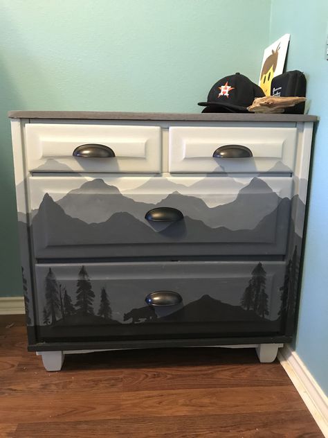 Took an old solid wood brown dresser, stained the top in grey stain, painted the rest in various shades of grey. Free hand paintings #daphnespaintedcreations Hand Painted Dressers Diy, Hand Painted Dresser Ideas, Grey Dresser Makeover, Painted Dresser Mountains, Gray And Stained Dresser, Diy Western Dresser Makeover, Dresser Painting Ideas, Western Painted Dressers, Grey Painted Dresser