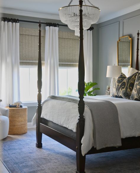 We love a bedroom that exudes a sense of timeless elegance! This bedroom features a wood bedframe, neutral wall paint, and a stunning chandelier that adds a touch of glamour to the space. The neutral blinds and flowing white curtains create a soothing ambiance while the soft rug adds a cozy feel to this inviting haven. Tap the image to see more bedroom design inspiration in our blog post at One Coast Design! Neutral Blinds, Four Poster Bedroom, Colonial Bedroom, Classic Bedroom Design, Stunning Chandelier, Home Design Magazines, Four Poster Bed, Traditional Bedroom Decor, Gorgeous Bedrooms