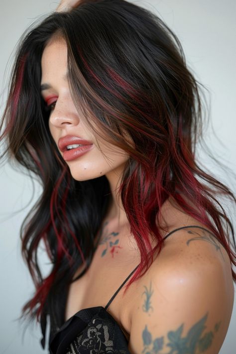 Woman with black hair featuring red highlights, showcasing a partial side profile, tattoos visible on her shoulder. Brown Hair With Brown Red Highlights, Red And Brown Highlights On Dark Hair, Vibrant Hair Highlights, Dark Brown And Red Hair Highlights, Cherry Red With Highlights, Dark Hair With Red Lowlights, Dark Brown Hair With Red Streaks, Dark Hair Red Money Piece, Red And Brown Hair Highlights