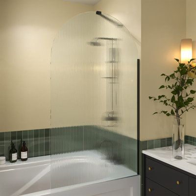 The tub door blends a fresh look with a sophisticated frameless design for an amazing value. The Victoria tub door combines 5/16 in. SGCC certified fluted tempered glass with a striking curved silhouette for a uniquely modern look in a single panel fixed door. Add a touch of brilliance to your bathroom with the gracefully curved lines of the Victoria tub door. Finish: Matte Black | House Of Brands 33" - W x 58" H Door Semi-Frameless Tub Door w / 58.0 H x 33.0 W x 0.31 D in blackTempered Glass in Glass Door Bathtub, Bathtub With Frameless Glass Door, Arched Glass Tub Door, Glass Bathtub Door, Bathtub With Fixed Glass Door, Rain Glass Bathtub Door, Glass Tub Enclosure, Bathtub With Glass Door, Matte Black House