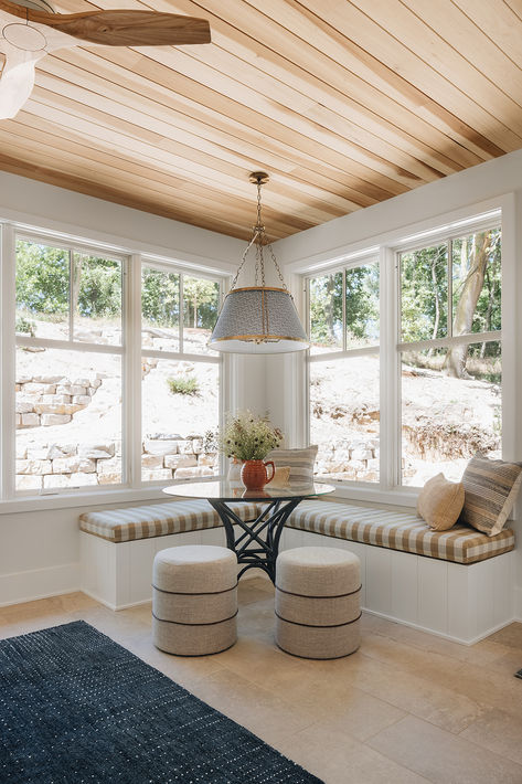 Drawing from the color palette just outside the windows of this sunroom, a tan striped window seat bench, beautiful wood plank ceiling detail and a navy blue rug provide a moment to sip coffee or play a card game.   Design by Two Hands Interiors. View more of this lake house on our website.  #lakehouse #sunroom Lakehouse Sunroom, Lake House Sunroom, North Carolina Beach House, House Sunroom, Card Game Design, Son House, Window Bench Seat, Wood Plank Ceiling, Plank Ceiling