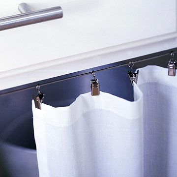 Base Cabinet Detail  -- A steel cable and clip-on rings make the curtain easy to install.    - an idea for the office? How To Hang Cabinet Curtains, Curtain Detail, Cabinet Curtains, Sew Apron, Cabinet Curtain, Sink Curtain, Cabinet Detail, Desk Base, Outdoor Cabinet