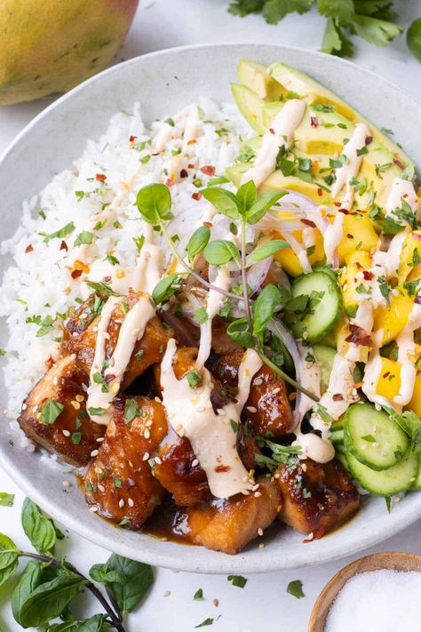 Teriyaki Salmon Rice Bowls are loaded with juicy mango, cucumber, avocado, fresh mint and cilantro on a bed of coconut rice and then finished with a spicy sriracha sauce. We've got a simple trick that makes the salmon oh-so-crispy, too! Perfect on busy weeknights or for meal prepping—you'll be the envy of all of your coworkers in the lunchroom! Salmon Bowl With Coconut Rice And Mango Salsa, Salmon Avocado Rice Bowl, Honey Siracha Salmon Rice Bowl, Salmon Rice Bowl Emily Mariko, Salmon Rice Edamame Bowl, Coconut Milk Rice, Salmon Rice Bowl, Salmon Bowl, Healthy Bowls Recipes