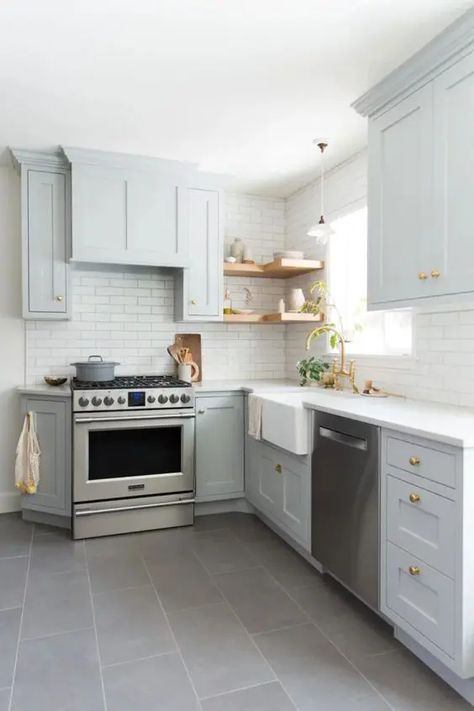 a light grey L shaped kitchen with open shelves, a white tile backsplash and gold handles is a very stylish and cozy space L Shaped Kitchen Interior, L Shaped Kitchen Cabinets, Modern L Shaped Kitchens, Kitchen With Open Shelves, Small U Shaped Kitchen, L Shape Kitchen Layout, Small L Shaped Kitchens, Brick Kitchen Backsplash, White Tile Backsplash