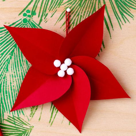 Make your own stunning holiday poinsettia to decorate this year's Christmas tree. To do it yourself, simply cut, fold, and glue red cardstock before adding a few white pom-poms to the center. Paper Poinsettia, Pretty Christmas Ornaments, Origami Christmas Ornament, White Christmas Ornaments, Diy Christmas Ornaments Easy, Paper Christmas Ornaments, Christmas Origami, Easy Christmas Decorations, Christmas Paper Crafts