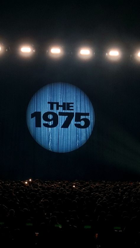 A curtain at a concert has the band logo "The 1975" projected onto it. The 1975 Background, The 1975 Aesthetic Poster, 1975 Concert Aesthetic, The 1975 Wallpaper Iphone, The 1975 Wallpaper Aesthetic, The 1975 Lockscreen Aesthetic, The1975 Aesthetic, Avicii Tattoo, The 1975 Aesthetic