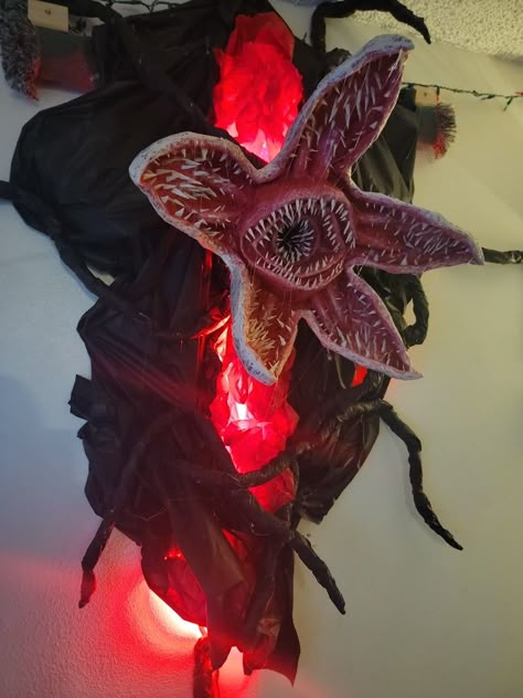 The portal was made out of plastic table cover. You can buy it by the roll. Added red tissue paper and red LED lights. The Demogorgon was paper mache with recycled cardboard, a Starbuck's cup in the mouth, lots of masking tape, LOTS of hot glue, and toilet paper for the outer layer skin effect. Paranormal Birthday Party, Stranger Things House Decor, Halloween Decorations Stranger Things, Stranger Things Portal Diy, Stranger Things Decoration Diy, Stranger Things Halloween Decorations Outdoor, Diy Demogorgon Decoration, Stranger Things Yard Decor, Stranger Things Door Decorations