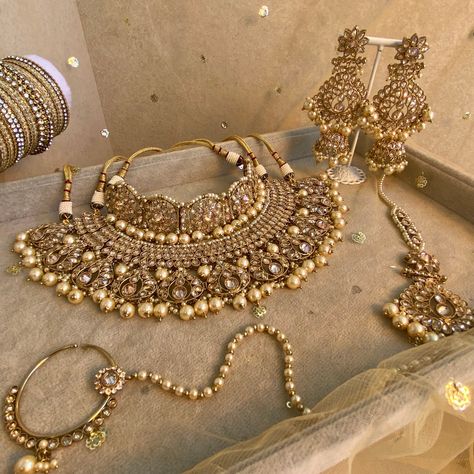 Antique gold bridal choker and necklace set with dazzling champagne zircon crystals and champagne pearl. The perfect wedding jewels.  Comes with choker, necklace, jhumka earrings, tikka and slide type nose ring.  Choker  1.5 inch length adjustable string Necklace 2.5 inch length with double adjustable string.  Earrings 4 Inch including jhumka length x 2 inch width   Tikka 3 inch pendant length plus 4.5 inch chain x 2 inch width  Nose ring which gentle hugs the nostril to secure (LEFT side only) Desi Bridal Jewelry Gold, Gold Bridal Accessories With Stone Work For Wedding, Heavy Gold Bridal Accessories For Wedding, Gold Bridal Accessories For Wedding And Festivals, Gold Kundan Bridal Necklace For Wedding, Gold Kundan Bridal Accessories For Reception, Gold Kundan Bridal Sets For Wedding, Gold Bridal Accessories For Reception And Festivals, Gold Hand-set Bridal Accessories For Reception