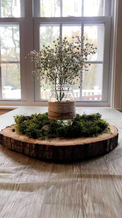 Centerpieces were made from a tree cut from the Mom to be’s yard, Moss was added on top to create a forest feel and pine cones were spray painted with gold glitter to add a pop of sparkle. The mason jars were reused from Mom and Dad to be’s wedding and babies breathe added a perfectly simple final touch to the tables. Table clothes were a white bitch print, actually being sold as Thanksgiving decor, but they worked perfectly with our theme! Tree Cut Centerpiece, Centerpieces Woodland Theme, Woodsy Baby Shower Table Centerpieces, Woodland Table Centerpieces, Pine Tree Baby Shower Theme, Forest Centerpiece Ideas, Woodland Centerpiece Ideas, Moss Table Decor, Tree Table Centerpieces