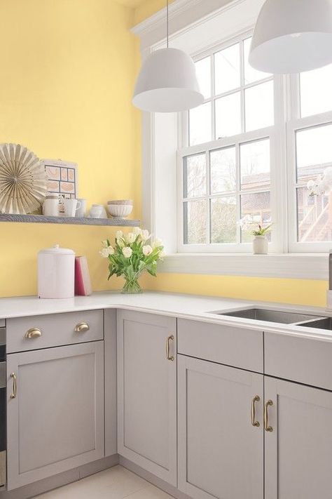 an airy kitchen with light yellow walls, dove grey cabinets and shelves, white pendant lamps and countertops Light Yellow Walls, Yellow Kitchen Walls, White Kitchen Countertops, Blue White Kitchens, Light Grey Kitchens, Yellow Cabinets, Yellow Kitchen Decor, Серая Кухня, Bold Kitchen