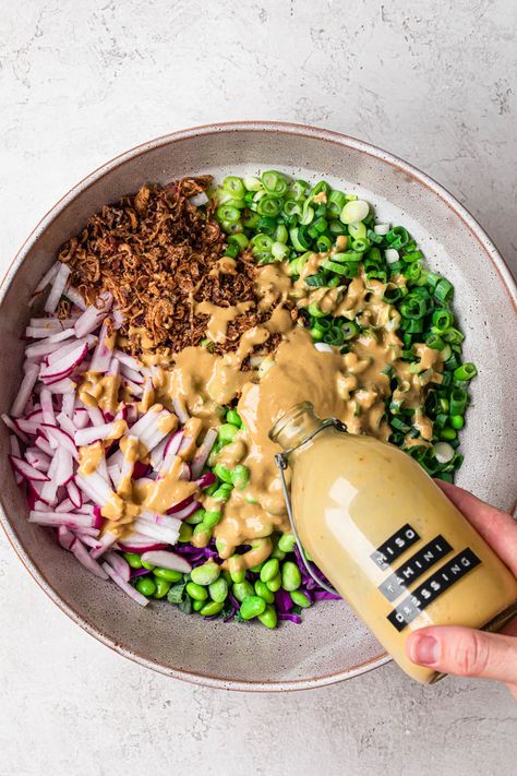 A bowl filled with salad, with tahini miso dressing being drizzled over the top from a glass bottle. Miso Paste Dressing, Miso Tahini Dressing, Avocado Tahini Dressing, Peanut Miso Dressing, Maple Miso Dressing, Tahini Apple Cider Vinegar Dressing, Cashew Miso Dressing, Tahini Salad Dressing, Miso Dressing