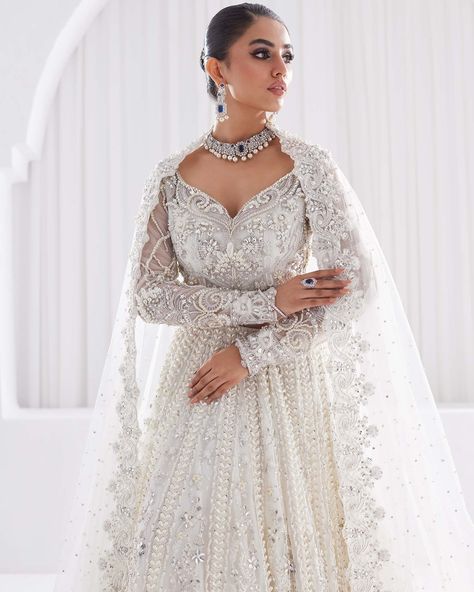 Serene white elegance unfolds in whispers of sheer layering, a symphony of delicacy. A vision to behold, a dream to wear. #pakistaniwedding #indianbridaldress #indianbridalwear #pakistanibridaldresses #pakistaniwedding #pakistanidresses #pakistaniclothing #pakistanidesignerwear #pakistanistyle #alifbymeem White And Silver Lehenga Bridal, White Wedding Dress With Indian Jewelry, White Wedding Lengha, White Lehenga Bridal, White Pakistani Bridal Dress, White Pakistani Wedding Dress, Aria Outfits, White Wedding Lehenga, White Indian Wedding Dress