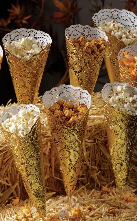 Whether you're celebrating #NationalPopcornDay or setting up a snack bar for a rustic wedding, this creative DIY popcorn display is sure to be remembered. How to: create cones out of gold foil doilies and secure shut. Push a skewer through the hole in the bottom of the cone so it comes about halfway through the cone. Fill with popcorn. Stick skewers in hay bails for a stand. Using different varieties of popcorn makes for a more fun looking display! Popcorn Display Ideas, Popcorn Display, Popcorn Store, Petite Desserts, Popcorn Ideas, Truffle Popcorn, Popcorn Decorations, Golden Bday, Christmas Banquet