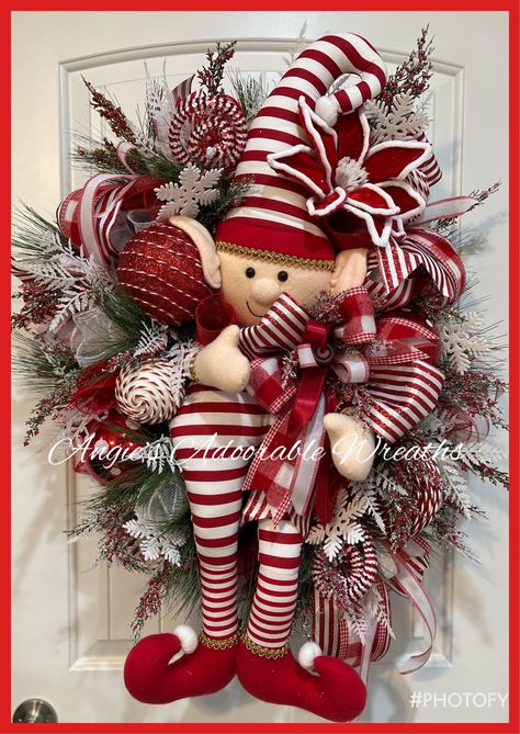 This cutie is created on a 24 inch Evergreen pine base surrounded with 10 inch deck  Taking centerstage is the custom hand zone, beautiful elf and peppermint stripes He is surrounded with beautiful textures of crazy Christmas greenery, shattered proof, ornaments for candy and peppermint rolls throughout and 4 inch wired ribbons from Steven another textures of wired rib This cutie will ship from Texas from pet and smoke free He is approximately 37 inches from top to bottom by 25 inches wide by 10 inches in depth Thank you for looking at my shop love, Angie Popular Christmas Wreaths 2024, Elf Wreaths, Red And White Christmas Wreath, Elf Christmas Wreath, Peppermint Wreath, Easter Deco Mesh Wreath, Elf Wreath, Deco Mesh Wreaths Tutorials, Christmas Peppermint