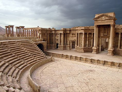 Theatre of Palmyra    Palmyra's Theatre was, until the 1950's, buried beneath the sand, however it has been restored continuously since then.    The freestanding stage facade of the theatre itself is designed along the lines of a palace entrance, complete with a royal door and smaller doors on either side.    During the Palmyra Festival, which runs from the end of April to the beginning of May, music and dance performances are held in the theatre. Pompeii Art, Museum Statues, Ancient Theater, Palmyra Syria, Royal Doors, Trinidad Carnival, Roman Theatre, Empire Romain, Roman Architecture