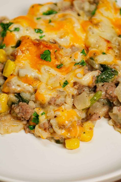 Cheesy Hamburger Rice Casserole is a hearty casserole loaded with ground beef, instant rice, frozen chopped spinach, corn, cream of mushroom soup, shredded cheddar and mozzarella cheese. Hamburger Veggie Casserole, Cheesy Ground Beef And Rice Casserole, Cooks Island, Ground Beef And Spinach, Hamburger Rice Casserole, Hamburger Rice, Corn Cream, Italian Hoagie, Hamburger Dishes