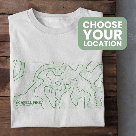 Celebrate your favourite outdoors location with a custom Contour Map T-Shirt! Perfect for any mountain lover, just let us know the location in the personalisation box. We will send you a proof of the design within 1-2 days so you can approve before print! The contour map is designed using online mapping data to make a unique, minimalistic visual that's perfect for an outdoors lover. This Unisex t-shirt is Vegan approved, Gots accredited and Fairwear Foundation certified which makes it a highly eco-friendly product. *Packaging This product is packaged in 100% plastic-free packaging that is compostable and degradable. *Delivery Our products are made to order and aim to have a 7 working day turn around or less for UK orders (Production and Royal Mail First Class Delivery)  Custom orders can t Sustainable Tshirt Design, T Shirt Mountain Design, Contemporary Tshirt Design, Map Shirt Design, Map Tshirt Design, Minimalistic Shirt Design, Outdoor Graphic Tees, Outdoor T Shirt Design, Nature Tshirt Design