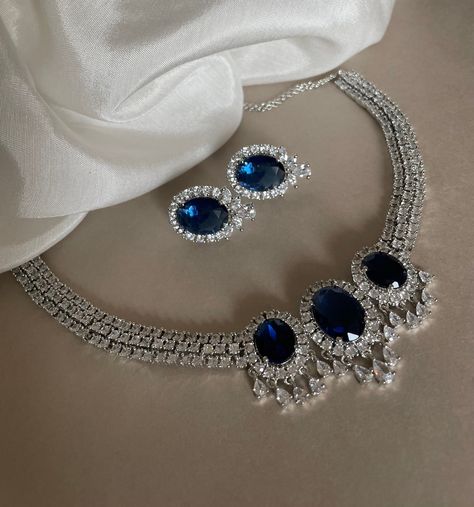 A luxurious and elegant Sapphire Blue Diamond necklace set beautifully crafted with American diamonds and blue stones. Perfect for any occasion! Details: Necklace Width at Centre with Drop-1.25 Inches Earrings Length-1 Inch Weight of Each Earring-5.5 grams All products are manufactured using traditional skills from our rich heritage of crafts.  The process of these crafts is essentially manual. Hence, any irregularities or variations are an inherent part of these handcrafting processes. Necklace Set Diamond, Blue Diamond Necklace, Indian Jewelry Set, Blue Jewelry Set, Terracotta Jewellery Designs, Cocktail Necklace, Blue Stone Necklace, Headpiece Jewelry, Terracotta Jewellery