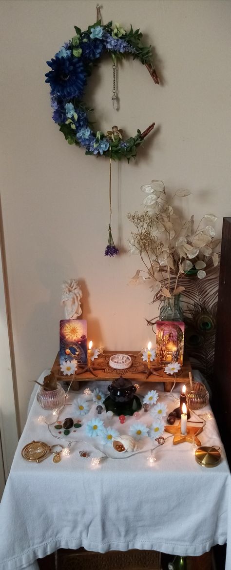 White table cloth, orange candles,  blue daisies for decoration, The Sun tarot card for representing the sun and The Chariot tarot card for transitioning into Cancer. Tigers eye and leaf shaped green aventurine crystals, gold objects, and a bee necklace. I've hung my lavender from a gold thread. Proud to put my new Stonehenge miniature on it too. Litha Altar, Litha Aesthetic, Pentecost, Season Of The Witch, Summer Solstice, Book Of Shadows, Tree Decorations, Witch