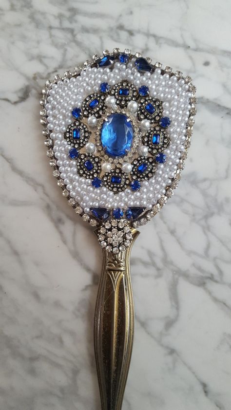 Vintage hand mirror I decorated in blue jewelry and pearls.  2019 by Sandy Hand Mirror Decorating Ideas, Bedazzled Ideas, Bride Trousseau, Vintage Hand Mirror, Candle Girl, Hand Mirrors, Bling Ideas, Art Deco Vanity, Diy Wine Glasses