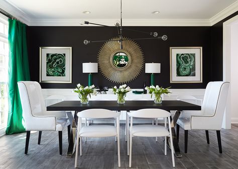 A stunning black, white, and emerald green design featuring a bold sputnik chandelier and white leather dining chairs. Malachite artwork and a gold sunburst chandelier complete the space. A formal dining room fit for an entertainer Dramatic Dining Room, White Dining Room Sets, Black And White Dining Room, Hunted Interior, White Wainscoting, Green Dining Room, Home Design Magazines, Black Dining, Black Dining Room