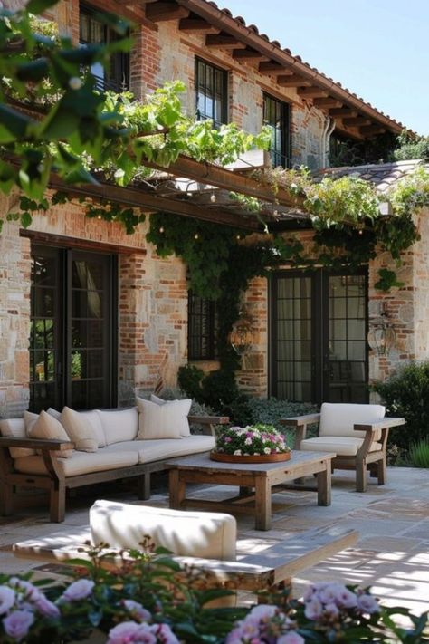 With its warm stone facade and vine-covered pergola, this Mediterranean patio retreat exudes charm and elegance. The soft beige seating and wooden furniture create a relaxing atmosphere perfect for gatherings. Colonial House Backyard Patio, Patio Deck Ideas, Patio Retreat, Cottage Patio, Mediterranean Patio, Modern Outdoor Lounge, Rustic Pergola, Rustic Mediterranean, Patio Decor Ideas